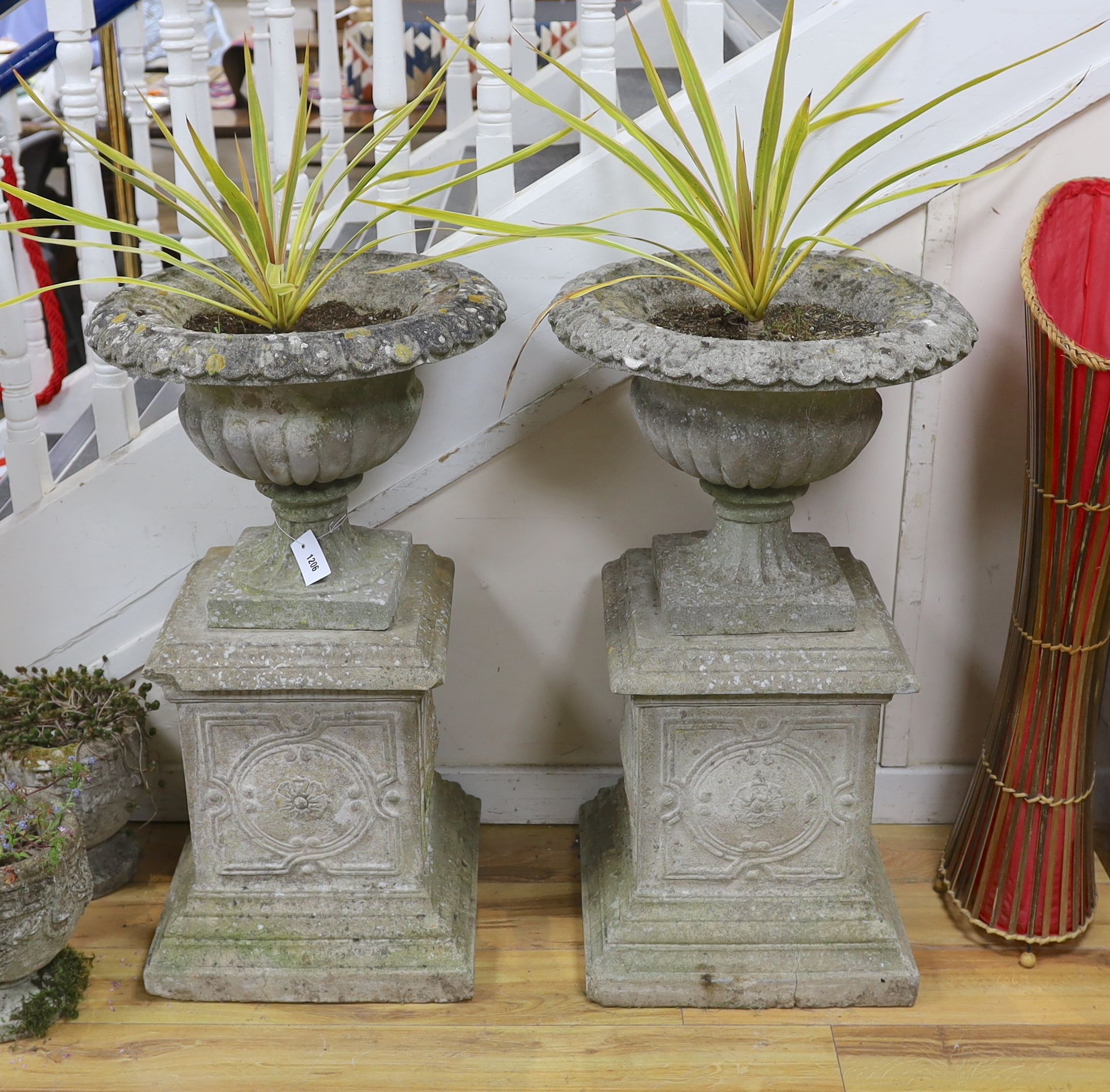 A pair of reconstituted stone campana garden urns on square plinth bases, height 90cm